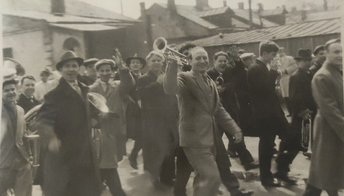 Оркестр завода заточных станков на первомайской демонстрации. 1950-1960-е годы. Дедушка Ирины — на первом плане в пальто и шляпе, с трубой под мышкой.